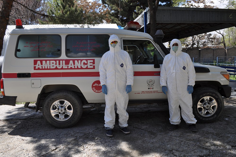 MDC Polyclinic staff in protective suits in front of the Polyclinic ambulance vehicle.
